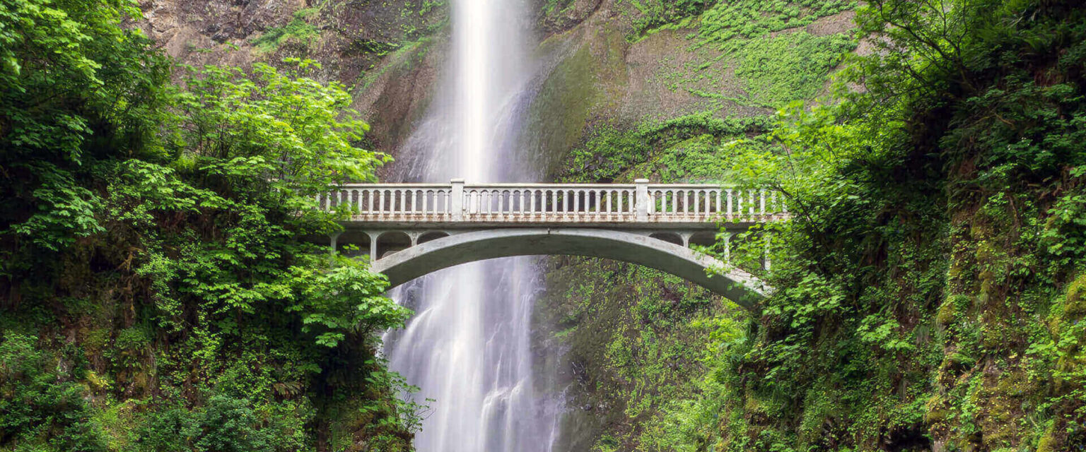 A bridge connecting two mountains with a waterfall in the background